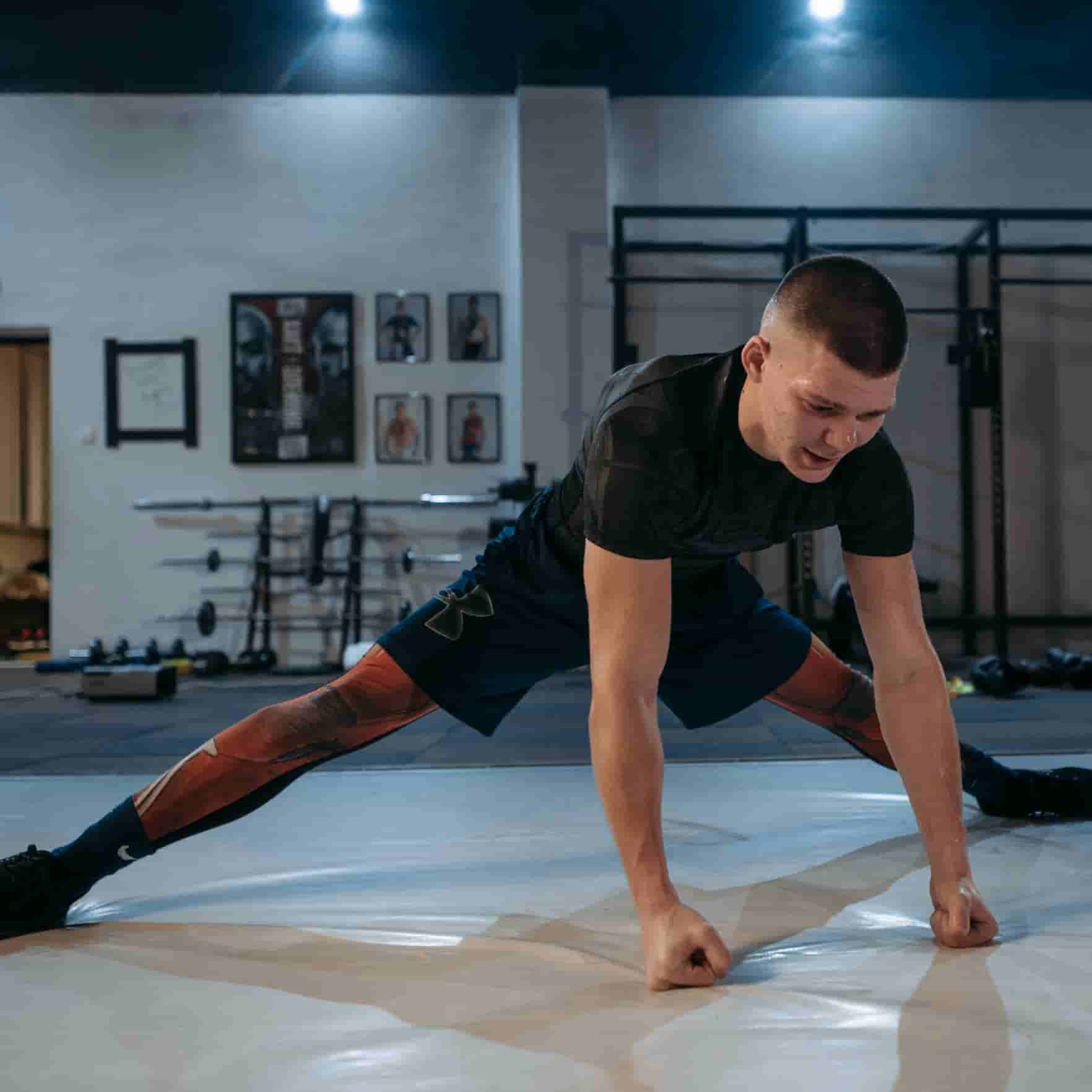 A man doing a half-splits stretch with his fists on the floor